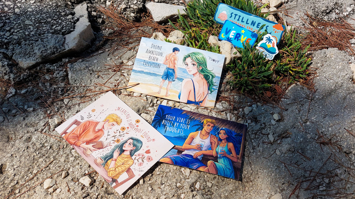 Three illustrated art prints with anime-style characters are arranged on a rocky, sunlit outdoor ground next to small green plants. The prints feature colorful artwork and text.